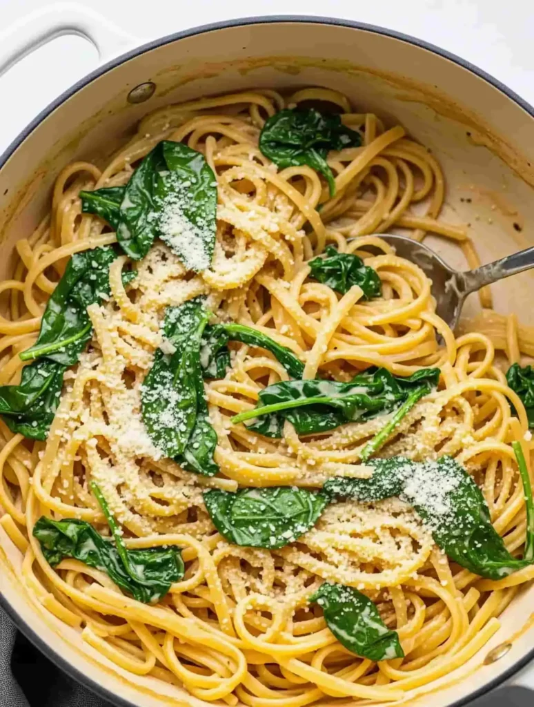  A creamy one-pot garlic parmesan linguine with fresh spinach mixed in, shown in a large pot ready to serve.