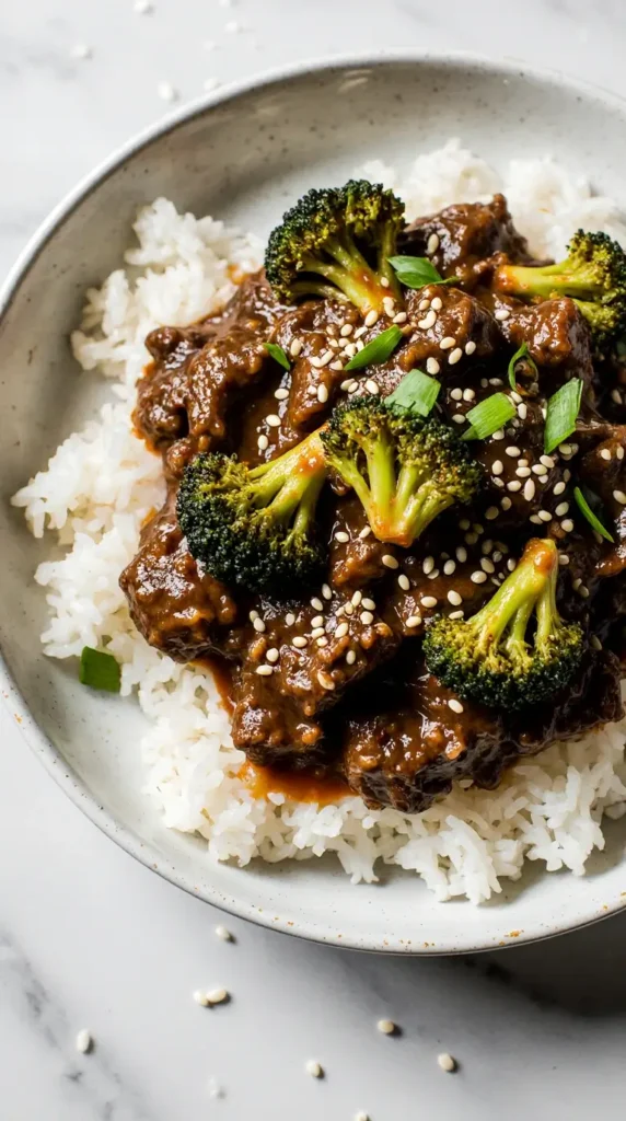 A close-up of a serving of classic beef and broccoli skillet with tender-crisp florets and savory ground beef over fluffy rice, garnished with sesame seeds.